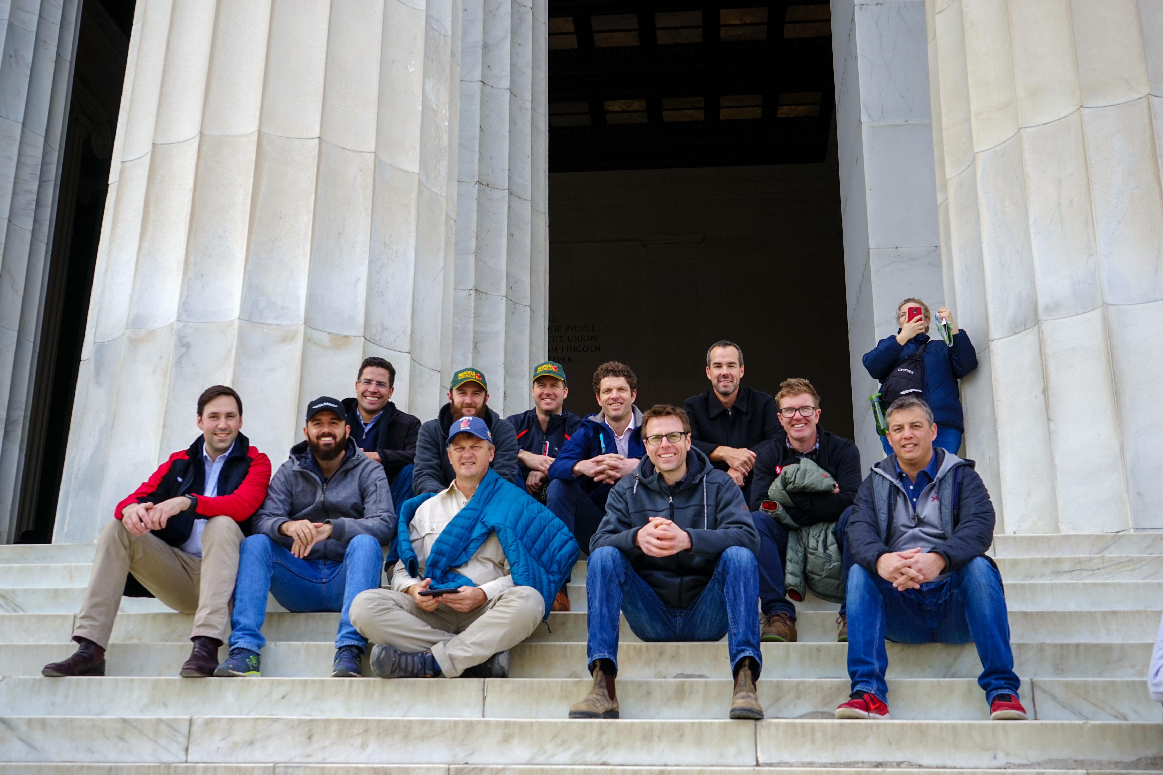 Group sat on steps in front of grand building with pillars